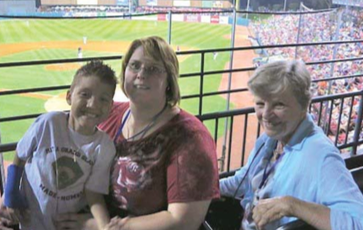 Image of Jayden with two women at a baseball game